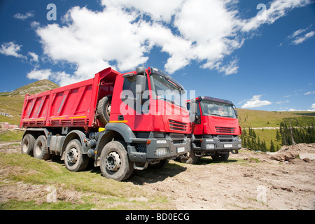 Zwei große rote Muldenkipper auf Baustelle in einem sonnigen Sommertag Stockfoto