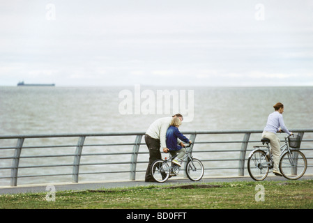 Vater Sohn lernen helfen, Fahrrad am Seepark, Mutter voraus Reiten Stockfoto