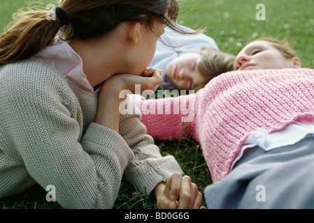 Mädchen, die nachdenklich beobachtet Mutter und Bruder liegen, ruhen auf dem Rasen Stockfoto