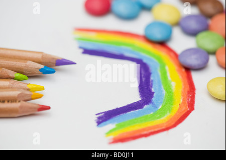 Childs, die Zeichnung eines Regenbogens mit Buntstifte und smarties Stockfoto