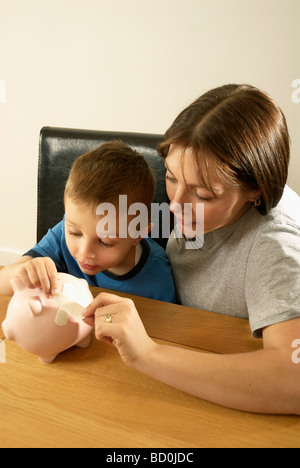 Mutter und Sohn reparieren Sparschwein Stockfoto