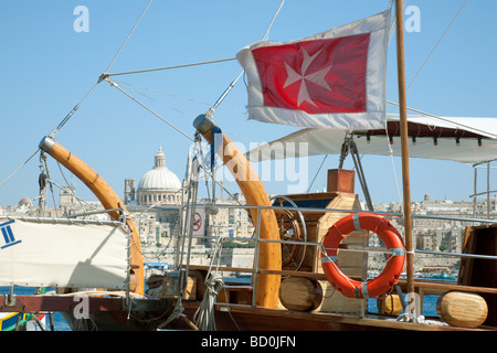 Die Malteser Kreuz-Flagge an Bord ein Segelboot mit Valletta im Hintergrund, Malta Stockfoto