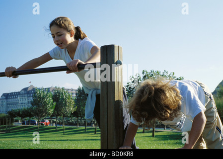 Mädchen spielen am Barren im park Stockfoto