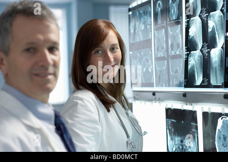 Zwei Ärzte, lächelnd, Röntgenstrahlen hinter Stockfoto