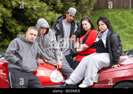 Bande von Jugendlichen sitzen auf Autos Stockfoto