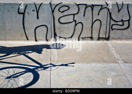 Schatten Sie auf Bürgersteig der Person mit dem Fahrrad, Graffiti an der Wand Stockfoto