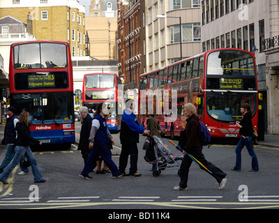 Menschen, die über die Straße mit roten Londoner Busse im Hintergrundbild schoss aus Oxford Street London UK Stockfoto