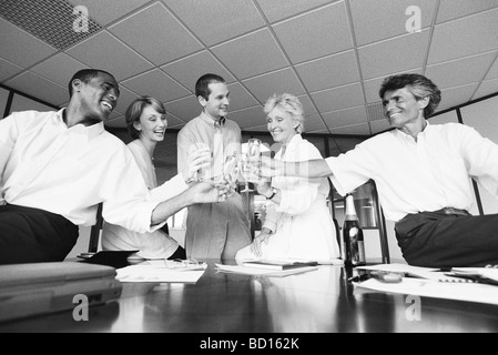 Geschäftspartnern klirrende Gläser, feiert mit Champagner im Büro Stockfoto