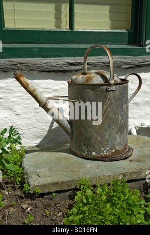 Alte Zink Gießkanne auf Stück Schiefer schließen im Garten England UK Vereinigtes Königreich GB Grossbritannien Stockfoto