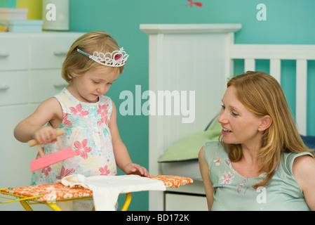 Kleine Mädchen spielen im Schlafzimmer mit Mutter, vorgibt, Eisen Stockfoto