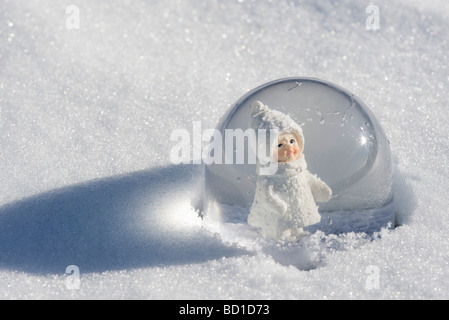 Schneekugel im Schnee, Figur von kleinen Mädchen tragen Wintermantel und Hut mit Blick Stockfoto