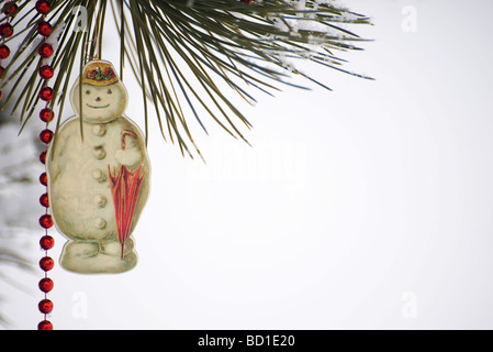 Snowman Christmas Ornament und wulstige Girlande von Schnee bedeckten Ast hängen Stockfoto