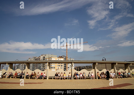 Touristen sitzen in der Sonne an der Strandpromenade in De Haan Belgien Stockfoto