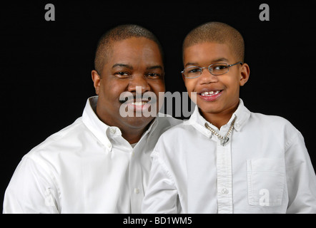 Vater und Sohn, die lächelnd auf einem schwarzen Hintergrund Stockfoto