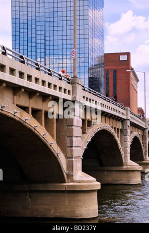 Ein Angler versucht sein Glück von einer Brücke in Grand Rapids des Hochhauses ist Amway Grand Plaza Hotel Stockfoto