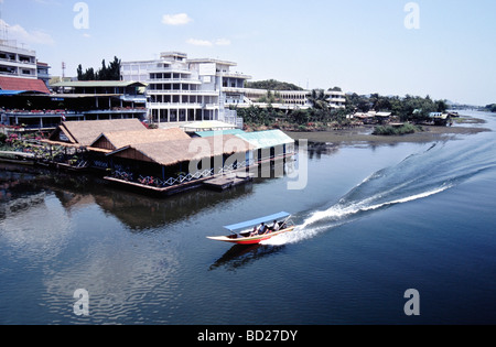 Ein Boot vorbei an schwimmenden Restaurants und Kriegsmuseum in der Nähe von Brücke über River Kwai in Kancanaburi Provinz in Thailand Stockfoto