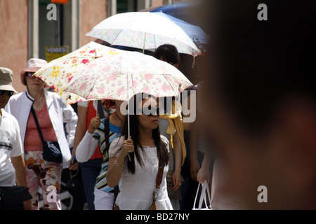 orientalische Touristengruppe mit Sonnenschirmen in der heißen Sonne in Rom Italien Stockfoto