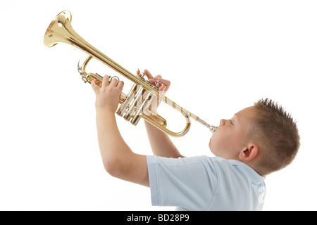 kleiner Junge bläst in eine Trompete vor weißem Hintergrund Stockfoto