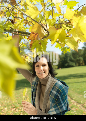 Frau auf der Suche durch Herbst Zweige Stockfoto