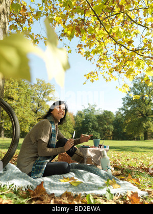 Frau Herbst Picknick unter Bäumen Stockfoto