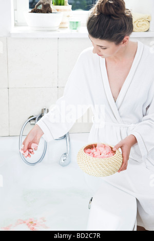 Frau wirft Rosenblätter in Bad Stockfoto