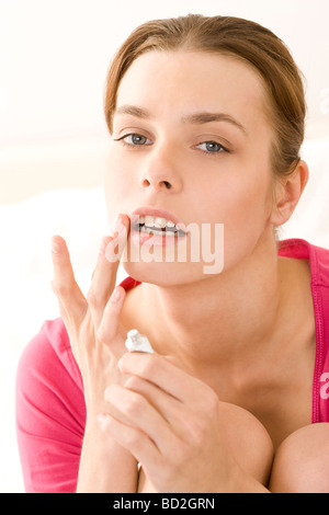 Junge Frau, die Anwendung der Salbe über herpes Stockfoto