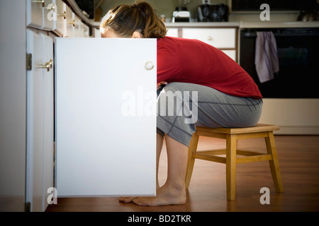 Frau auf der Suche im Küchenschrank Stockfoto