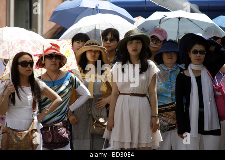 orientalische Touristengruppe mit Sonnenschirmen in der heißen Sonne in Rom Italien Stockfoto