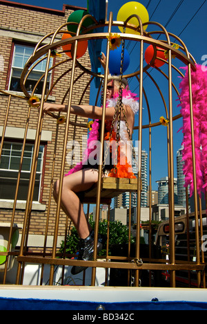 Extravagante Teilnehmer auf Schaukel im Käfig auf Float bei Gay-Pride-Parade Stockfoto