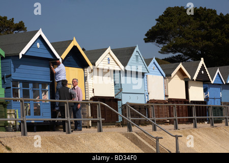 Drei 3 Männer bereiten die Strandhütte für den Sommer in Mudeford Spit Hengistbury Head, Christchurch, Bournemouth, Dorset UK im Frühjahr vor Stockfoto