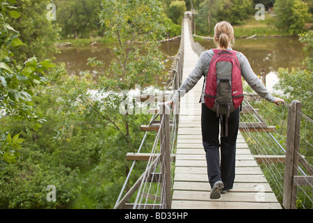 Woman Hiker Crossing a Swing Bridge, Souris, Manitoba, Kanada.