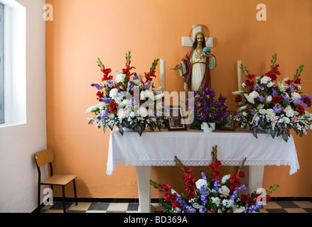 Im Inneren kleine Kapelle am Friedhof in Spanien. Altar mit Blumen und Statue von Jesus Christus. Stockfoto