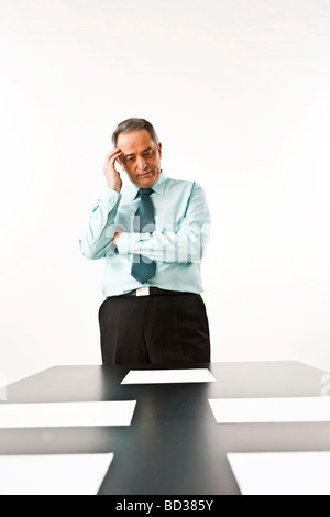 Manager stand vor seinem Schreibtisch, Grübeln Stockfoto
