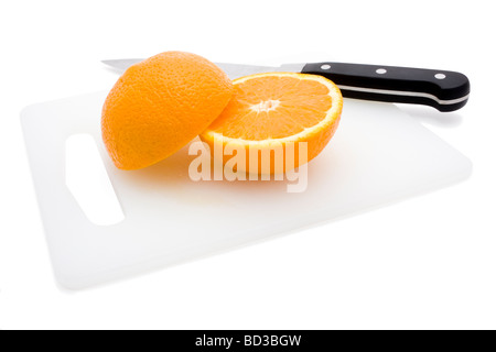 Frisch geschnittene orangene Hälften auf weiß Schneidebrett mit Messer Stockfoto