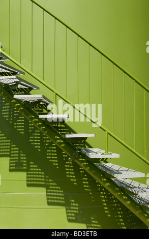 Industrielle Metallstufen an der grünen Wand Stockfoto