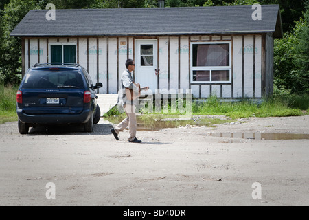 Ein junger Mann spielt Gitarre, während wir geht von einem bescheidenen Haus in der Algonquin Anicinape Gemeinschaft von Kitcisakik in Quebec Kanada Stockfoto