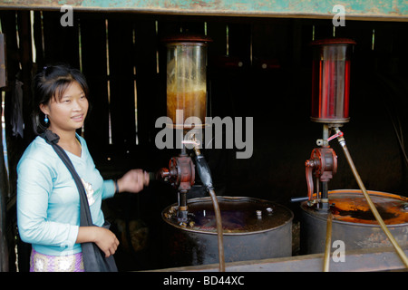 Xieng Khouang, Laos, 2006: Ein junges Mädchen verkauft Benzin mit einer Handpumpe befestigt ein Barrel Erdöl Stockfoto