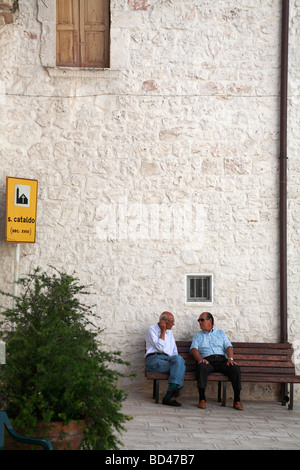 Zwei ältere italienische Männer saß auf einer Bank im Gespräch außerhalb der Kathedrale, Centro Storico, Cisternino, Apulien, Italien. Stockfoto