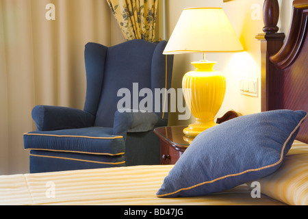 Detail aus einem Luxus-Hotel-Schlafzimmer mit Bett, Stuhl und Nachttischlampe Stockfoto