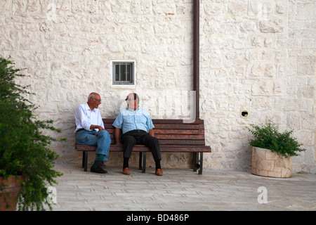 Zwei ältere italienische Männer saßen auf einer Bank sprechen, Cisternino, Apulien, Italien. Stockfoto