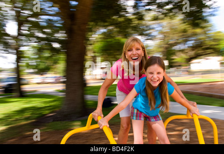 Mutter und Tochter Spaß drehend auf Fahrt auf Spielplatz Stockfoto