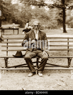 Gut gekleidete Greis warten auf Parkbank Stockfoto