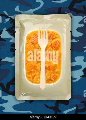 Eine militärische Lebensmittel rationieren Paket mit einer Gabel auf einem Hintergrund von blauen Tarnung, in Scheiben geschnittenen Möhren in sauce Stockfoto