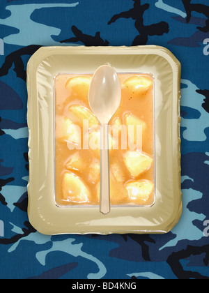 Eine militärische Lebensmittel rationieren Paket mit einem Löffel auf dem Hintergrund eines blauen Tarnung, in Scheiben geschnittenen Pfirsiche Stockfoto