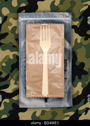 Ein Kunststoff-militärische Lebensmittel rationieren Paket mit einer Plastik Gabel auf einem Hintergrund von grünen Tarnung Stockfoto