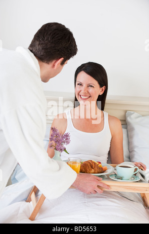 Ein Mann, eine Frau-Frühstück im Bett zu bringen Stockfoto