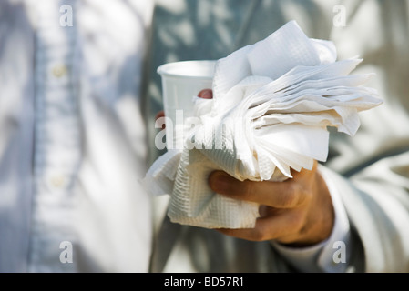 Hand mit Einweg-Becher, Papierservietten Stockfoto