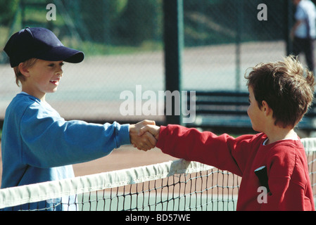 Mädchen Händeschütteln bei Net auf Tennisplatz Stockfoto