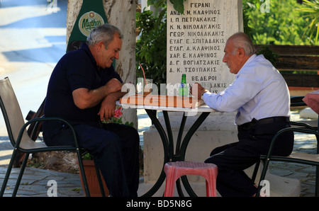 Zwei griechische Männer spielen Backgammon oder Tavla neben dem Kriegerdenkmal auf einem schattigen Platz in Prines Kreta Stockfoto