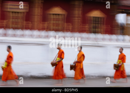 Mönche zu Fuß die Straße in der Dämmerung sammeln Geschenke von Lebensmitteln, Luang Prabang, Laos Stockfoto